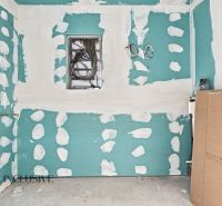 An unfinished room in a family house with exposed electrical wires and drywall.