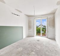 Interior of a family house with an incomplete wall and a view of the garden.