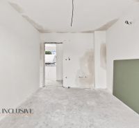 A white room in a family house with two open doors and a green element on the wall.