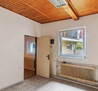 A room with white walls, a wooden ceiling, and a carpet in a family house.