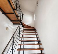 A staircase with a metal railing and steps with a wooden decor in a family house.