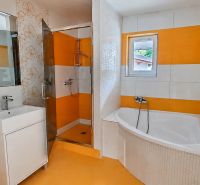 A bathroom with orange and white tiles, a bathtub, and a shower in a family house.
