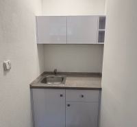 A small kitchenette in commercial premises with a light-colored sink cabinet.