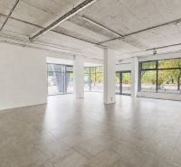 Spacious commercial spaces with large glass walls, flooring, and concrete ceiling.