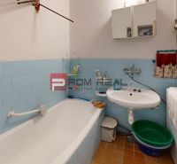 A bathroom in a family house with a bathtub, sink, washing machine, and blue tiles.