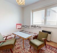 A room in a family house with two armchairs and a table on a carpet.