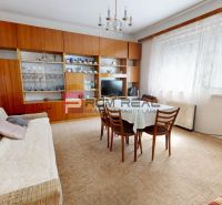 Living room in a family house with a sofa, dining table, and a cabinet with dishes.