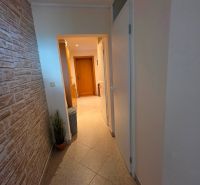 A hallway with stone cladding and tiles in a 3-room apartment.