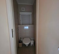A toilet with light ceramic tiles in a 3-room apartment.