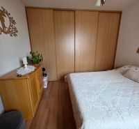 A bedroom in a three-room apartment with a double bed, a wardrobe, and a floor with a wooden decor.