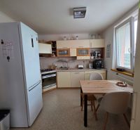 A kitchen in a 3-room apartment with a dining table and appliances, floor with a wooden decor.