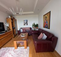 Living room with wood-patterned flooring, leather sofa, and an icon in a 3-room apartment.