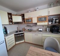 A kitchen in a 3-room apartment with modern appliances and wooden cabinets.