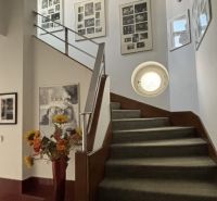 The staircase of the villa with a carpet, flower decorations, and artistic frames on the walls.