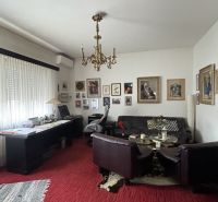 Living room in a villa with a red carpet, sofa, and paintings on the walls.