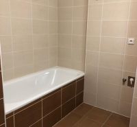 A bathroom in a 2-room apartment with a bathtub and beige tiles.