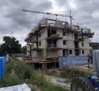 Construction of a residential complex in Beluša with an unfinished 3-room apartment and a construction crane.