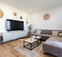 Living room in a family house with a wooden decor floor and a large gray sofa.