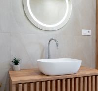 A bathroom in a family house with a wooden decor floor and a round mirror.