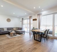 Living room with wood-patterned flooring, large sofa, and dining table in a family house.