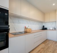 A kitchen in a family house with a wooden decor floor and light-colored furniture.