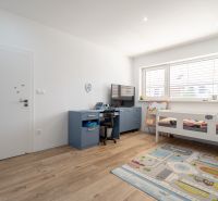 Children's room in a family house with a bed, table, and floor with a wooden decor.