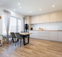 A bright kitchen of a family house with a wooden decor floor and a dining table.
