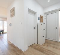 Entrance hallway of a family house with a wooden decor floor and a well-lit dining room.
