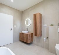 A bathroom in a family house with wooden decor and a round mirror.