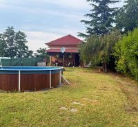 The exterior of the cottage in Komárno with a pool and a garden full of greenery.
