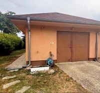 The exterior of the cottage in Komárno with a garage surrounded by a lawn.