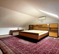 Attic room with a bed, carpet, and air conditioning in a cottage.