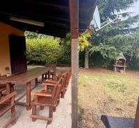 A covered terrace at the cottage in Komárno with seating and a garden grill.