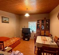 Living room in a cottage with a kitchen table, sofa, and wooden decor flooring.