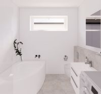 White bathroom in a family house with a bathtub, mirror, and toilet.