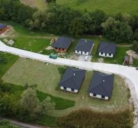 Aerial view of six family houses in Prašník surrounded by greenery and an access road.