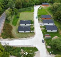 Family houses in the village of Prašník surrounded by greenery and an access road.