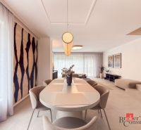 Dining room in a 4-room apartment with large windows and a decorative carpet on the wall.