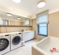 A bathroom in a 4-room apartment with a washing machine, dryer, bathtub, and mirror cabinet.