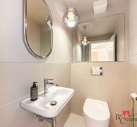 A bathroom with a mirror, sink, and toilet in a 4-room apartment.