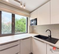 A kitchen in a 4-room apartment, with white cabinets and a black sink.