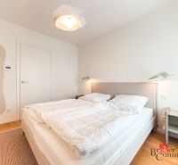 A bedroom in a 4-room apartment with an upholstered bed and a wooden decor floor.