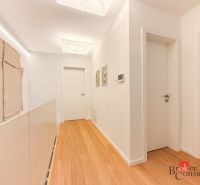 A corridor with a wooden decor floor in a 4-room apartment, white doors and walls.