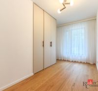 A room with a wooden decor floor, wardrobes, and curtains in a 4-room apartment.