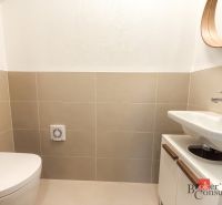 Bathroom with toilet, sink, mirror, and beige tiles in a 4-room apartment.