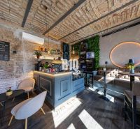 Interior of a gastro space with a bar counter, brick walls, and a wooden decor floor.