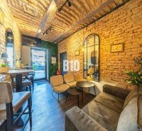 Interior of a gastro space with brick walls, comfortable seating, and a wooden-patterned floor.