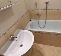 Bathroom with a bathtub and a sink in a 3-room apartment with light tiles.