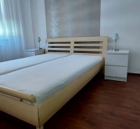 Bedroom with a bed and nightstands, wooden decor flooring in a 3-room apartment.