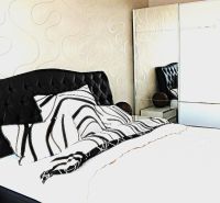 Bedroom in a 3-room apartment with a black headboard and a mirrored wardrobe.
